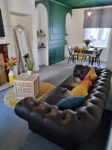 a living room with a black leather couch with colorful pillows at Junctions Way by Tŷ SA -3 bed in Newport in Newport