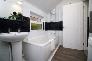 a white bathroom with a sink and a bath tub at Adamsdown Lodge by Tŷ SA in Cardiff