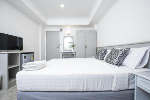 a white bedroom with a large bed and a tv at Chaipat Hotel in Khon Kaen