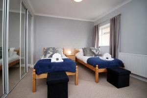 a bedroom with two beds with blue sheets and a window at Keats Retreat by Tŷ SA in Newport