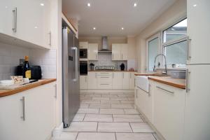 a kitchen with white cabinets and a tile floor at Keats Retreat by Tŷ SA in Newport