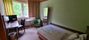 een slaapkamer met een bed, een bureau en een televisie bij Hotel Zur Erholung & Restaurant Amme's Landhaus in Eicklingen