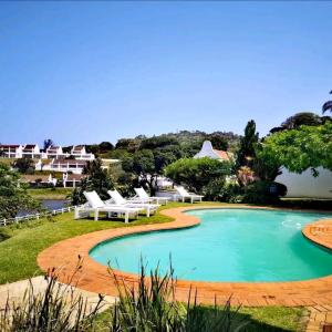 a swimming pool with lounge chairs and a body of water at Villa 44, The Estuary Country Estate, Port Edward in Port Edward