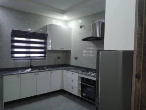 uma cozinha com armários brancos e um frigorífico de aço inoxidável em Dixonlux Apartments em Abuja