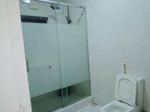 uma casa de banho com um WC e uma cabina de duche em vidro. em Dixonlux Apartments em Abuja