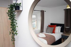 a mirror reflecting a bedroom with a bed and a window at Kingsway House by Tŷ SA - Spacious 4bed in Newport in Newport