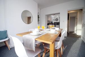 ein Esszimmer mit einem Holztisch und weißen Stühlen in der Unterkunft Kingsway House by Tŷ SA - Spacious 4bed in Newport in Newport