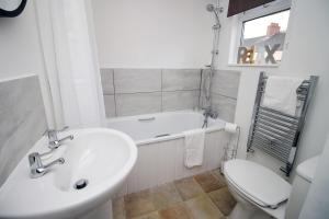 a bathroom with a sink and a tub and a toilet at Kingsway House by Tŷ SA - Spacious 4bed in Newport in Newport