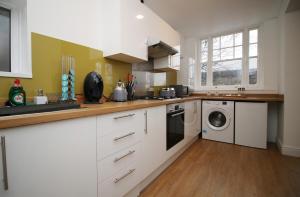 eine Küche mit weißen Schränken, einer Waschmaschine und einem Trockner in der Unterkunft Flora Suites by Tŷ SA in Newport