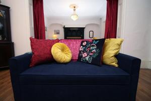 a blue couch with colorful pillows on it at Flora Suites by Tŷ SA in Newport