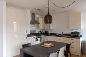 a kitchen with a black table and white cabinets at GuestReady - London Urban Retreat at East End in London