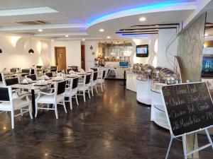 un restaurante con mesas y sillas blancas y una pizarra en Falettis Express DHA en Lahore