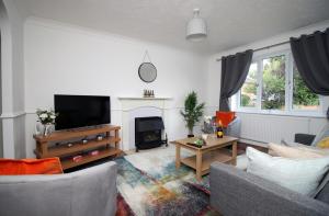 a living room with a couch and a tv at Langstone Close by Tŷ SA in Llanwern
