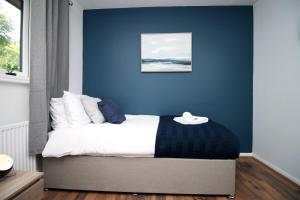 1 dormitorio con una pared azul y 1 cama en Langstone Close by Tŷ SA en Llanwern