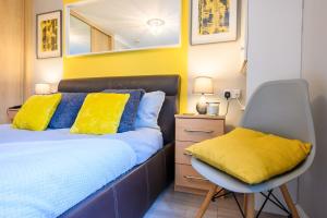 a bedroom with a bed with yellow pillows and a chair at Stadium Way by Tŷ SA -Cardiff Central with Parking in Cardiff