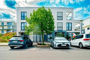 茨文考Appartements am Hafen的两辆汽车停在一栋建筑前的停车场