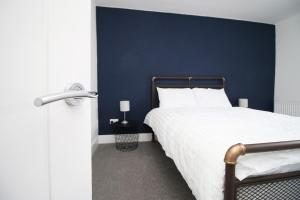 Schlafzimmer mit einem Bett mit blauer Wand in der Unterkunft Station Terrace by Tŷ SA - 3 Bed in Mountain Ash in Quakers Yard