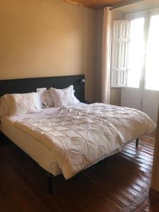 a bed with white sheets and pillows in a bedroom at Pension Casa Simon in Tríacastela