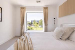 NorthfieldModern Mansion in Lightsview By Host Solutions的卧室里有一张白色的大床，床边有一扇窗户