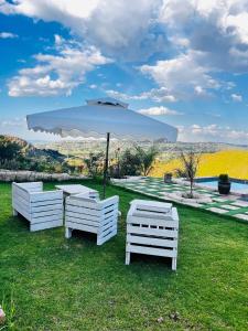 a group of white chairs and an umbrella in the grass at Maupa Mountain view in Krugersdorp