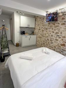 a bedroom with a white bed and a stone wall at 1900 Apartments Ioannina in Ioannina