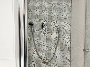 y baño alicatado con ducha y manguera. en Nice Apartment in Düsseldorf, en Düsseldorf