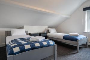 a bedroom with two beds with blue and white sheets at Maindee Parade by Tŷ SA in Newport