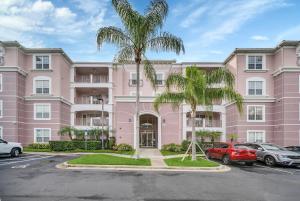 un bâtiment rose avec des voitures garées dans un parking dans l'établissement Vista Cay 81 by Top Villas, à Orlando