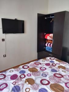 a bed in a room with a bedspread with a tv at appartement à larache in Larache