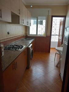 een keuken met een fornuis, een wastafel en een fornuis top oven bij appartement à larache in Larache