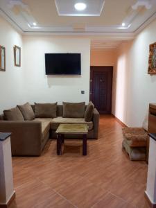 ein Wohnzimmer mit einem Sofa und einem TV an der Wand in der Unterkunft appartement à larache in Larache