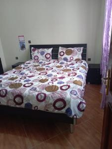 ein Bett mit einer Bettdecke und Kissen im Schlafzimmer in der Unterkunft appartement à larache in Larache