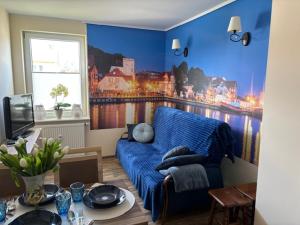 a living room with a blue couch and a window at Apartament z Tarasem in Ustka