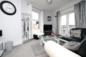 a living room with a couch and a clock on the wall at Stunning sea views - Barry's Retreat by Tŷ SA in Barry