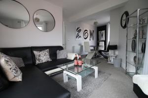 a living room with a black couch and a glass table at Stunning sea views - Barry's Retreat by Tŷ SA in Barry