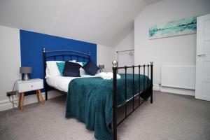 a bedroom with a bed with a blue wall at Stunning sea views - Barry's Retreat by Tŷ SA in Barry