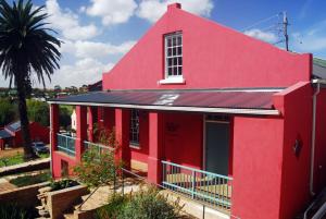 a red house with a window and a palm tree at The Restio Country Guesthouse in Napier