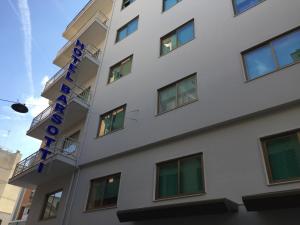 a white building with a blue sign on it at Hotel Barsotti in Brindisi