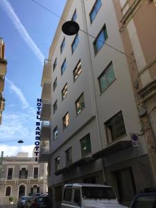 Un alto edificio bianco con un orologio sopra di Hotel Barsotti a Brindisi