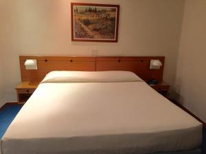 a large white bed in a room with two night stands at Hotel Barsotti in Brindisi