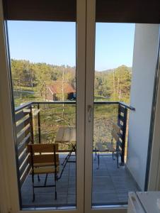 - une vue depuis la porte d'un balcon avec 2 chaises dans l'établissement Apartmani Jezero Divčibare, à Divčibare