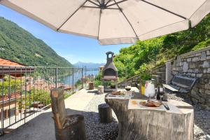 a patio with a table and an umbrella at Appartamento Tivano in Argegno