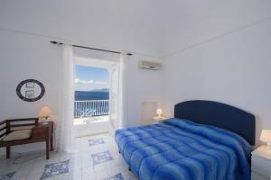 a bedroom with a blue bed and a balcony at Villa Panorama in Praiano