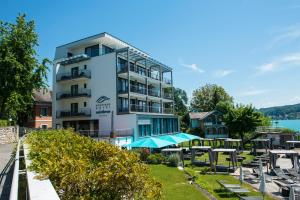 a hotel with tables and umbrellas in front of a building at Boutique Apartments Velden in Velden am Wörthersee