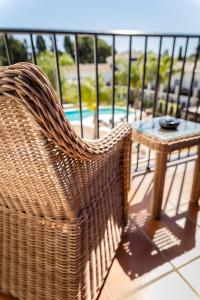 een rieten stoel op een balkon met een tafel bij Paloma Blanca Boutique Hotel- Adults Recommended in Marbella