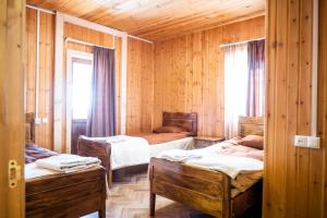 een kamer met drie bedden in een houten kamer bij Guesthouse Ushguli Maspindzeli in Ushguli