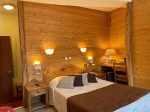 Hotel de Bourgogne في ساليو: غرفة نوم بسرير في جدار خشبي