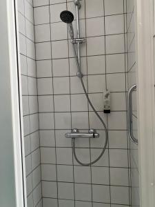 een douche met een slang aan een betegelde muur bij Hotel Fauwater in Kasterlee