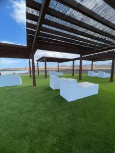 a pavilion with white benches on a green field at Villa Arcano Boho Chic in La Oliva +7 photos