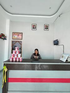 una mujer de pie detrás de un mostrador con pasteles rosados en Horas Hotel, en Sibolga